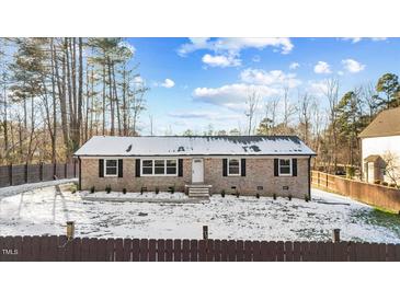 Charming brick home featuring classic black shutters and a well-maintained yard partially covered in snow at 7103 Big Horn Dr, Hillsborough, NC 27278