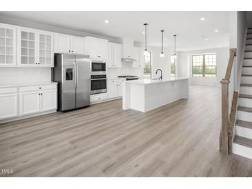 Bright kitchen features white cabinets, stainless steel appliances, large island and durable hard surface floors at 1402 Chowan Ave, Durham, NC 27713