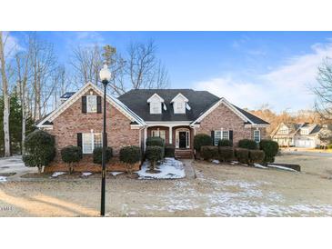 Charming brick home with dormers, manicured shrubs, and snowy front lawn at 101 Mantle Dr, Clayton, NC 27527