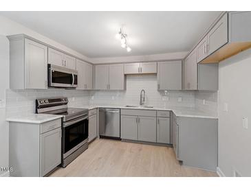 Bright kitchen features stainless steel appliances, gray cabinets, stone countertops, and subway tile backsplash at 1213 Freeman Dr, Sanford, NC 27330