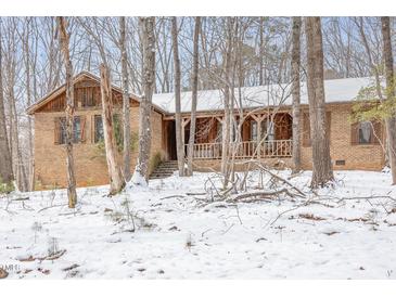 Charming brick home featuring a covered porch and wintery wooded surroundings at 3412 Hackney Ct, Raleigh, NC 27613