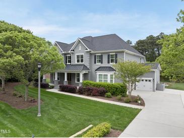Stunning two-story home featuring a well-manicured lawn, complemented by an attached two-car garage and a tree-lined front yard at 1005 Keith Rd, Wake Forest, NC 27587