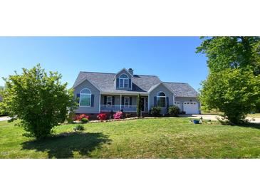 Charming home with a well-manicured lawn, flowering bushes, and a welcoming front porch, perfect for relaxing at 1317 Justin Oaks Ct, Willow Springs, NC 27592