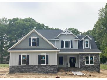Charming two-story home with stone accents and a neatly landscaped yard under a cloudy sky at 1663 Keith Hills Rd, Lillington, NC 27546