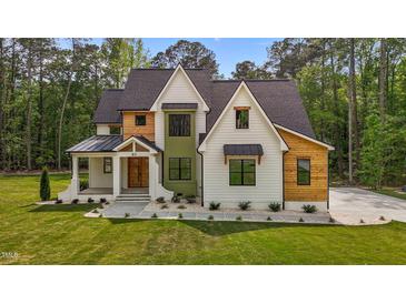 Beautifully designed two-story home with wood and white siding and a well-manicured lawn at 80 Carnation Rd, Youngsville, NC 27596