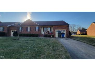 Charming brick home with a well-manicured lawn and inviting front porch at 1811 Meadow Green Dr, Graham, NC 27253