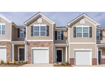 Townhouse with a beige exterior, brick accents, and an attached one car garage at 1916 Frost Dr, Haw River, NC 27258
