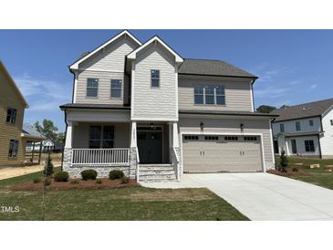 Charming two-story home boasts a two-car garage, inviting front porch, and manicured lawn at 3521 Amelia Grace Dr # 67, Fuquay Varina, NC 27526