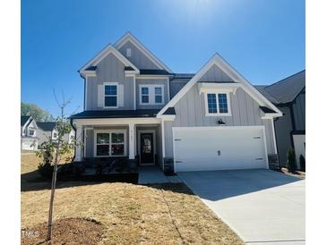 Charming two-story home featuring a two-car garage, light gray siding, and a well-manicured front lawn under a clear blue sky at 5161 Church Rd # 17, New Hill, NC 27562