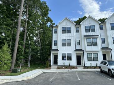Modern white townhome with black-framed windows and doors, surrounded by lush greenery at 1551 Crescent Townes Way, Raleigh, NC 27604