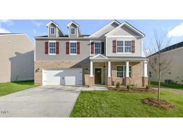 Charming two-story home featuring brick accents, red shutters, a two-car garage and a well-manicured front lawn at 1752 Post Oak Dr, Haw River, NC 27258