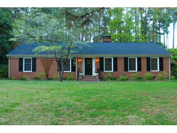 Charming brick home featuring a manicured lawn and classic black shutters at 711 Stuart Dr, Sanford, NC 27330