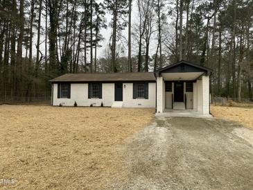 Charming renovated home with painted brick and covered porch entrance, enveloped by mature trees at 905 Spruce Pine Trl, Durham, NC 27705