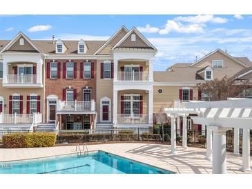 Beautiful townhome exterior view showcases double balconies and red shutters near a refreshing community pool at 10321 Sablewood Dr # 108, Raleigh, NC 27617