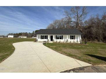 Charming single-story home with a white exterior, black shutters, and a long concrete driveway at 107 Faucette Dr, Selma, NC 27576