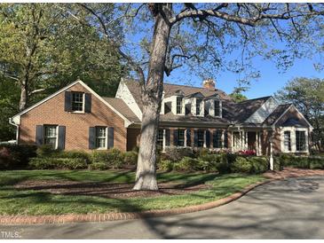 Charming brick home featuring manicured landscaping, black shutters, and a brick driveway at 30 Brookside Place, Durham, NC 27705