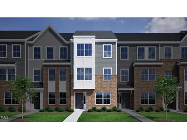 Charming new construction townhome with brick facade, gray siding, and a well manicured front yard at 332 Chesapeak Commons St # 141, Garner, NC 27529