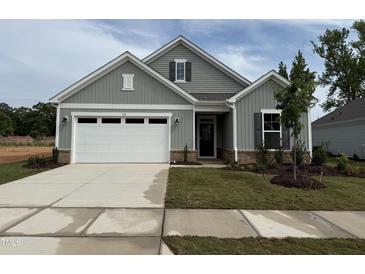 Charming single-Gathering home featuring a two-car garage, manicured lawn, and inviting front entrance at 142 Oban Dr, Homesite 135, Sanford, NC 27330