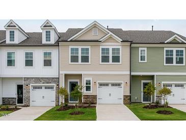 Attractive townhome showcases a neutral exterior, a one car garage, and manicured front lawn at 52 Shay St, Angier, NC 27501