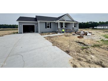 Charming gray home with a black roof, a driveway, and under-construction landscaping at 82 Asher Pointe Way, Benson, NC 27504