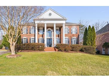 Stately brick home with large columns, black shutters, and well-maintained landscaping on a sunny day at 2110 Crigan Bluff Dr, Cary, NC 27513