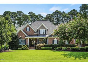 Charming brick home with manicured lawn, mature trees, and lush landscaping at 5708 Creekfall Ln, Fuquay Varina, NC 27526