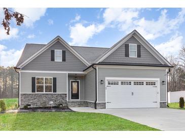Charming gray home with a two-car garage, gray roof, and manicured lawn and professional landscaping at 60 Pintail Lane Ln, Youngsville, NC 27596