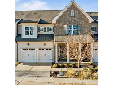 Charming townhome featuring a two-car garage and inviting front porch, complemented by manicured landscaping at 1027 Laurelwood Dr, Durham, NC 27705