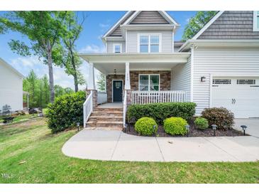 Charming two-story home featuring a covered porch with stone accents and manicured landscaping at 115 Lockamy Ln, Youngsville, NC 27596