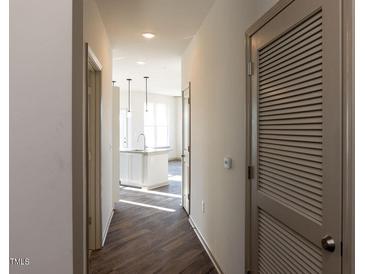 Bright hallway featuring wood floors leads to a modern kitchen with stainless steel appliances at 2300 Gathering Sq Ct, Fuquay Varina, NC 27526