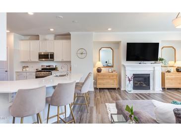 Stylish living room with modern kitchen, fireplace, and elegant decor, perfect for comfortable living and entertaining at 2929 Great Lawn Rd, Apex, NC 27502