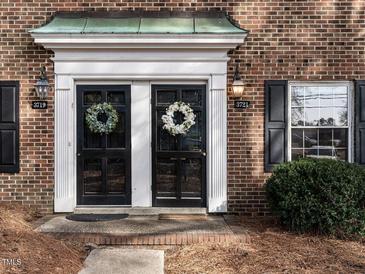Charming brick home featuring dual front doors with wreaths and black shutters at 3721 Browning Pl, Raleigh, NC 27609