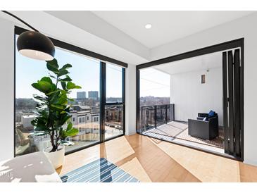 Bright living room featuring a balcony with city views and hardwood floors at 523 S West St # 409, Raleigh, NC 27601
