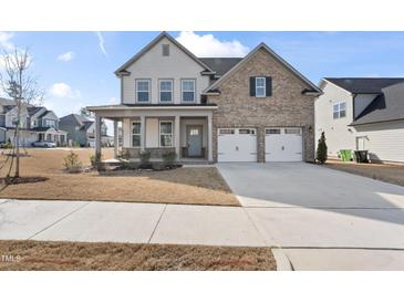 Charming two-story home with a brick and siding exterior, a two-car garage, and a welcoming front porch at 652 Marion Hills Way, Knightdale, NC 27545