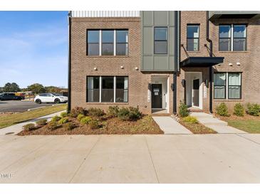 Inviting brick townhome featuring well-manicured landscaping and sidewalk leading to the front door at 1259 Shaw View Alley # 101, Raleigh, NC 27601