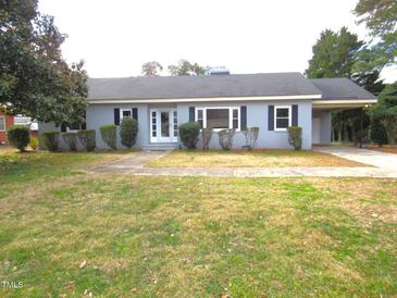 Charming single-story home with grey brick, manicured bushes, and a covered driveway at 136 Dogwood Trl, Wendell, NC 27591