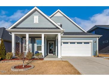 Charming blue home featuring a well-manicured lawn, inviting front porch, and a two-car garage at 244 Bevis Marks Dr, Fuquay Varina, NC 27526