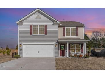 Charming two-story home with a two-car garage and a cozy front porch with chairs and a welcoming wreath at 2815 E Brookwood Ct, Creedmoor, NC 27522