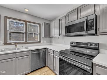 Well-lit kitchen featuring modern appliances, gray cabinets and light countertops at 6036 Epping Forest Dr, Raleigh, NC 27613