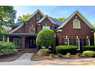 Stately brick home showcasing a manicured lawn, classic shutters and a welcoming, covered front porch at 6532 Wakefalls Dr, Wake Forest, NC 27587