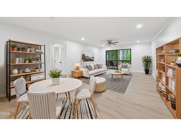 Bright living room with hardwood floors, neutral decor, and sliding door access to a deck at 689 Pine Ridge Pl, Raleigh, NC 27609