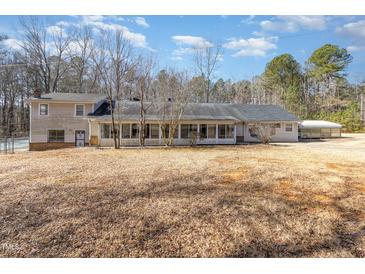 An exterior rear view of a house featuring an enclosed porch and a spacious backyard at 10611 Quail Roost Rd, Bahama, NC 27503
