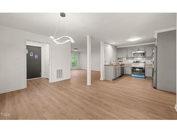 Open concept living room and kitchen area with hardwood floors and modern lighting fixture at 1411 Rosewood St, Durham, NC 27701
