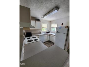 This kitchen features white appliances, white cabinets, light countertops, and a breakfast bar at 1440 Collegeview Ave # 301, Raleigh, NC 27606