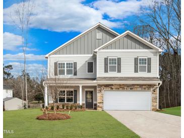 Charming two-story home with a stone-accented garage and covered porch, set against a blue sky at 219 E American Merigold Dr # 45, Benson, NC 27504