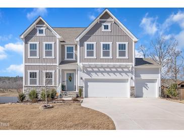 Charming two-story home with a three-car garage, stone accents, and a well-manicured lawn at 492 Arlie Ln, Lillington, NC 27546