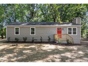 Charming one-story home with gray siding, red front door, and well-maintained landscaping at 567 Howard Tant Rd, Zebulon, NC 27597