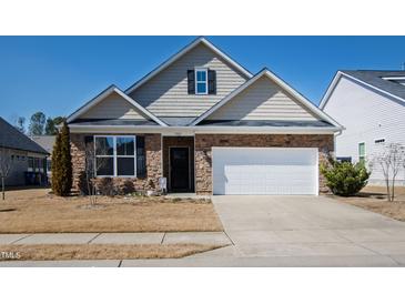 Charming two-story home featuring a stone facade, a two-car garage, and a well-maintained front yard at 7525 Poplar Meadow Ln, Raleigh, NC 27616