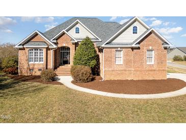 Charming brick home featuring a landscaped front yard, arched entryway, and multiple windows at 7800 Twin Pines Way, Fuquay Varina, NC 27526