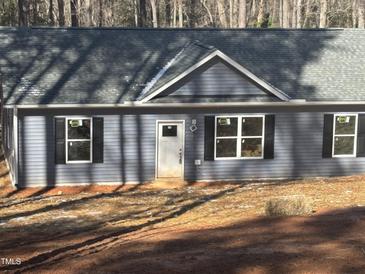 Newly constructed home showcasing light blue siding, black shutters, and a grey roof at 810 Jasmine Rd, Fuquay Varina, NC 27526